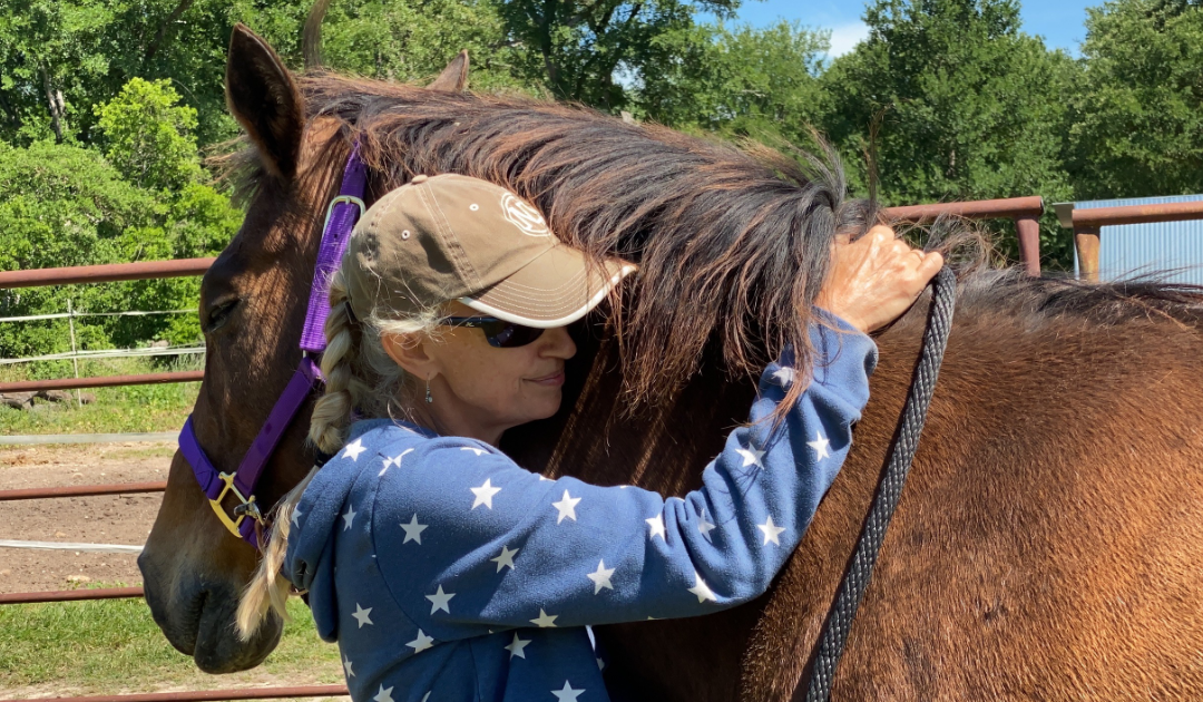 woman in blue spotted long sleeve hugging horse